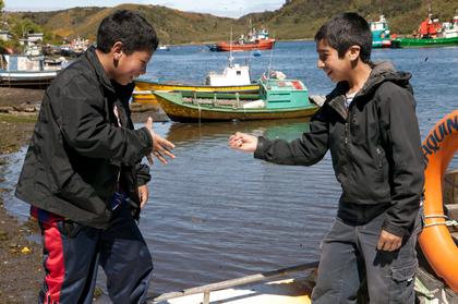 Claudio en Miguel spelen "Steen-papier-schaar" op het dek van een vissersboot.