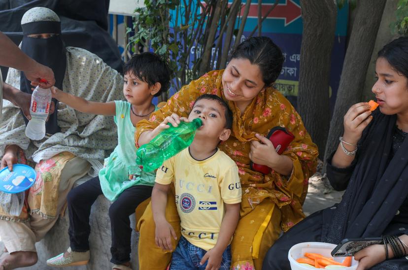epa11293419 Children drink from water bottles during the heatwave in Dhaka, Bangladesh